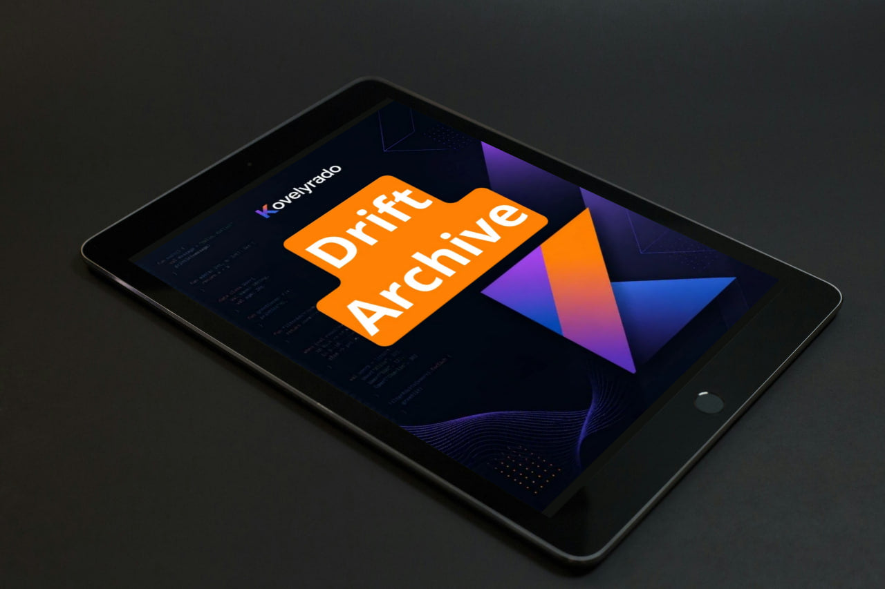 A black tablet device shown at an angle on a dark surface, displaying a colorful app-style interface with the text 'Koyepino' and a large orange 'Drift Archive' graphic.